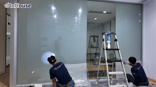 InHouse の2名が調光フィルムを施工 調光フィルム ガラス壁を丁寧に作業 — マヒドン大学——学長棟の会議室に機関水準のスマートプライバシー